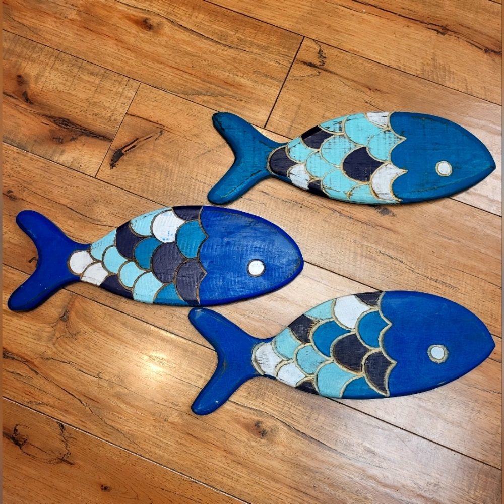 Three cute wooden, painted fish, designed to be hung on a wall.